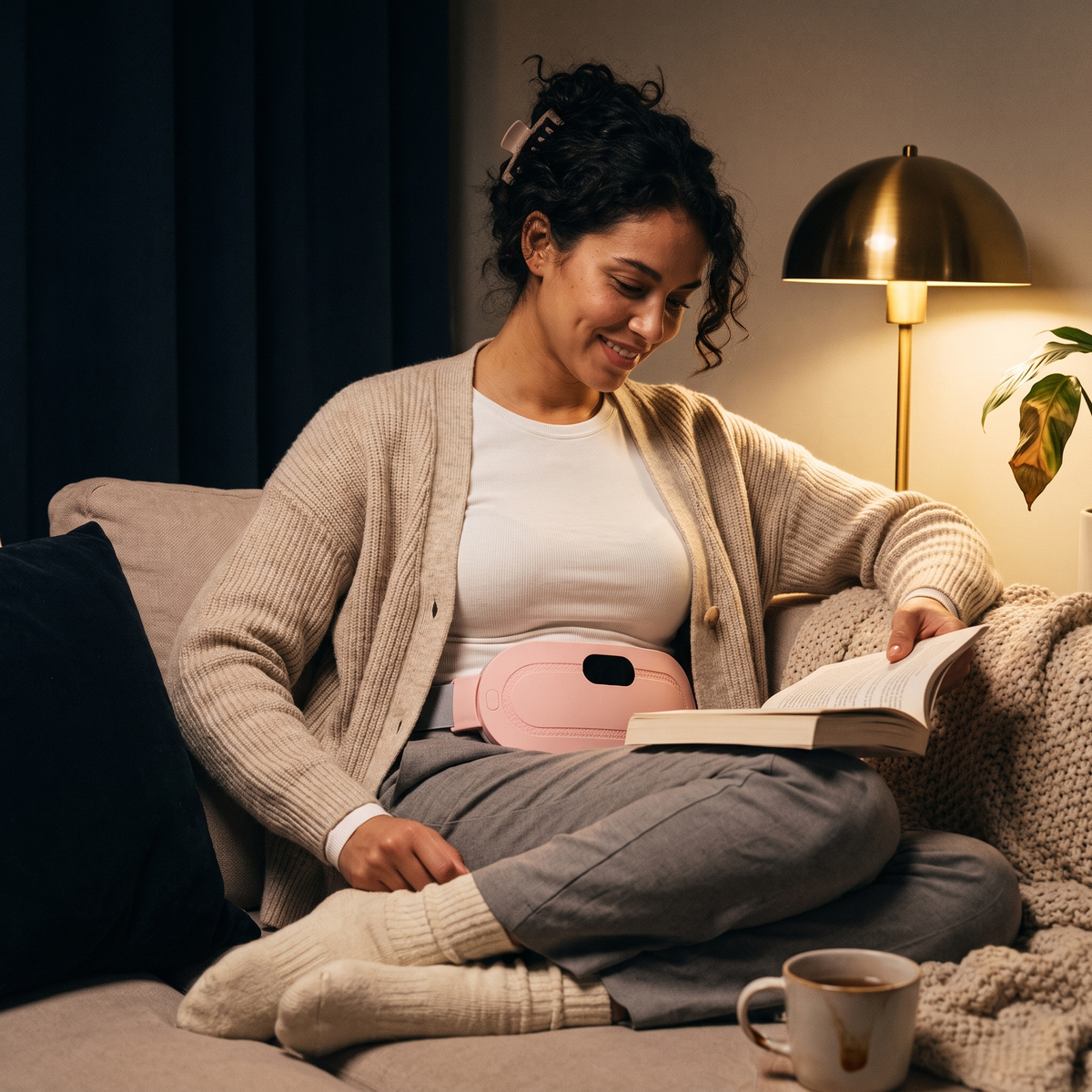 Woman reading on the sofa wearing the Kalmi heat belt