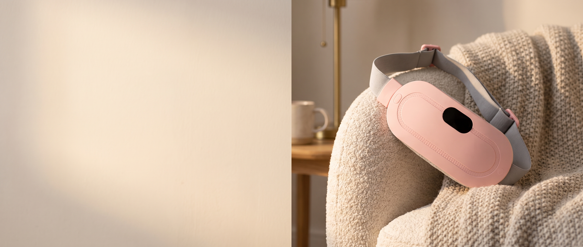 Kalmi pink cordless heat and massage belt resting on a cream armchair in warm evening light